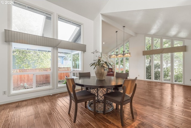 dining area featuring a chandelier, vaulted ceiling with beams, hardwood / wood-style flooring, and plenty of natural light