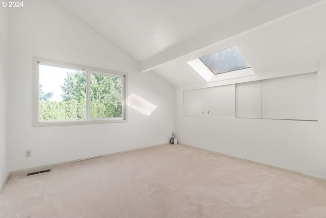 additional living space featuring light colored carpet and lofted ceiling with skylight