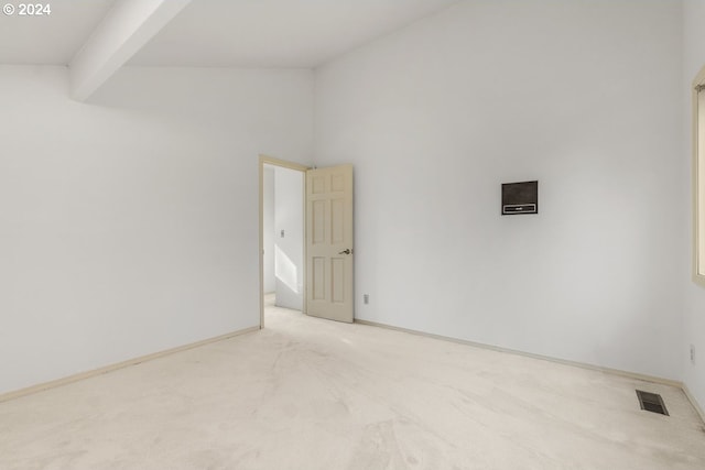 carpeted empty room with beamed ceiling and high vaulted ceiling