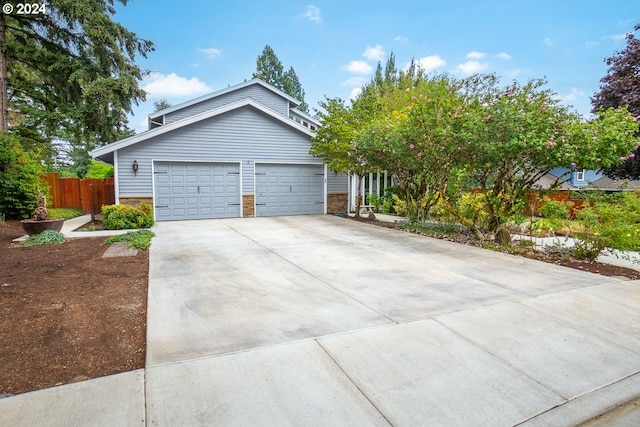 view of front of property featuring a garage, fence, and concrete driveway