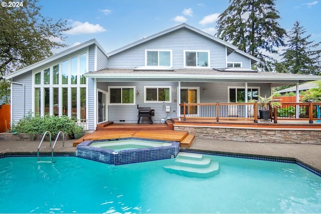 rear view of house featuring a pool with hot tub