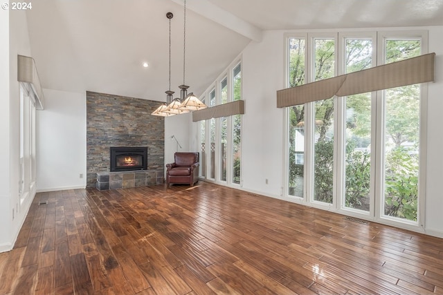 unfurnished living room with a chandelier, high vaulted ceiling, a stone fireplace, and dark wood-type flooring