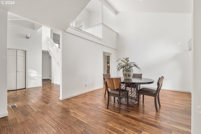 dining room featuring hardwood / wood-style flooring, beam ceiling, and high vaulted ceiling