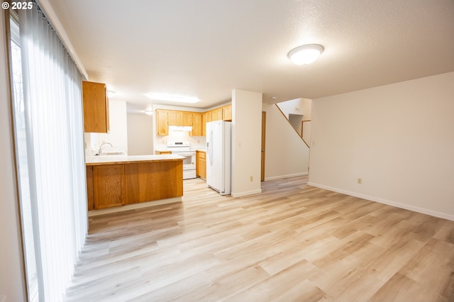 kitchen featuring kitchen peninsula, light hardwood / wood-style flooring, sink, white appliances, and a textured ceiling