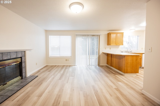 unfurnished living room featuring sink, light hardwood / wood-style flooring, and a tiled fireplace
