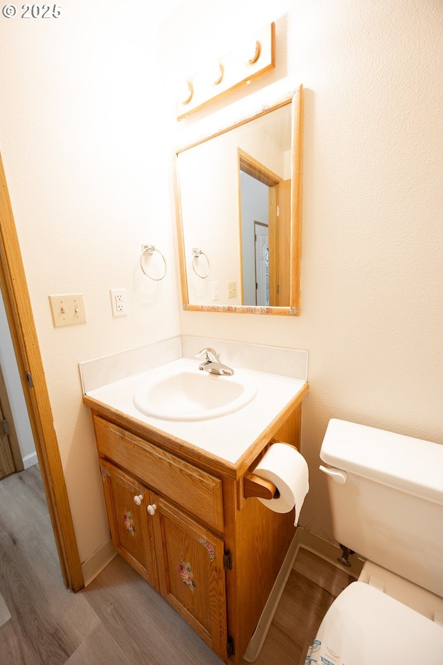 bathroom featuring vanity, toilet, and hardwood / wood-style flooring