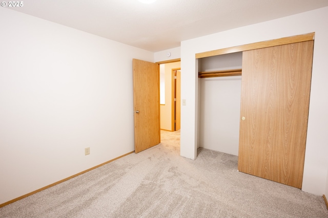 unfurnished bedroom with light colored carpet and a closet