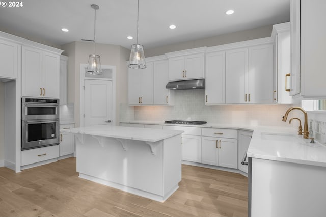 kitchen with a center island, light hardwood / wood-style flooring, white cabinets, and appliances with stainless steel finishes