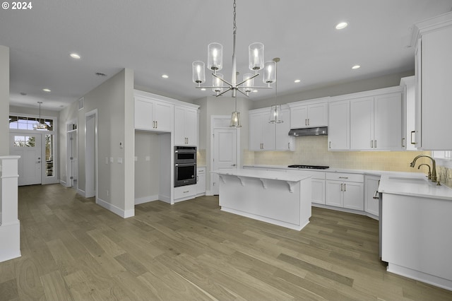 kitchen with white cabinets, a center island, light hardwood / wood-style floors, and sink