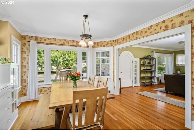 dining space with light hardwood / wood-style flooring, crown molding, and a notable chandelier