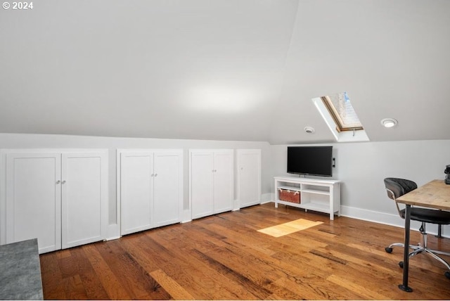 home office featuring vaulted ceiling with skylight and hardwood / wood-style floors