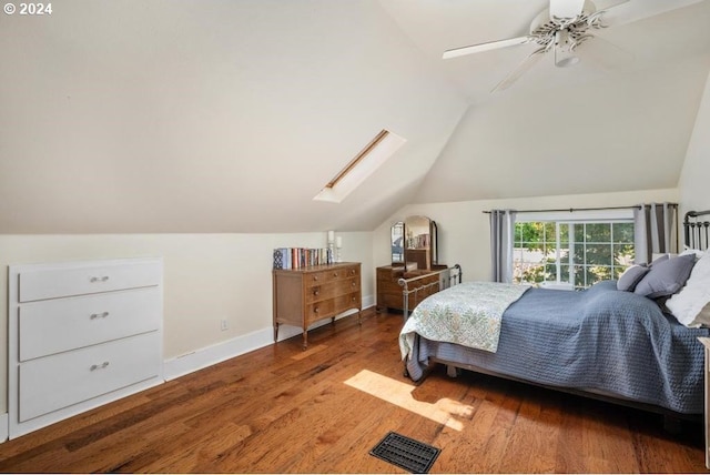 bedroom with ceiling fan, vaulted ceiling with skylight, and hardwood / wood-style flooring