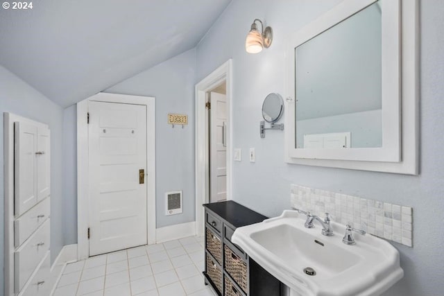 bathroom featuring lofted ceiling, tile patterned floors, backsplash, and sink