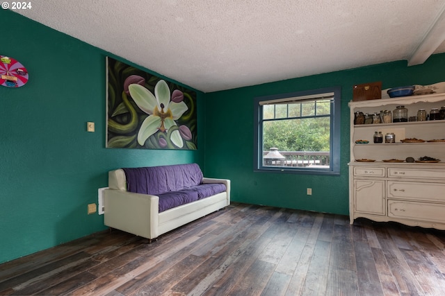 unfurnished room featuring beam ceiling, dark wood-type flooring, and a textured ceiling