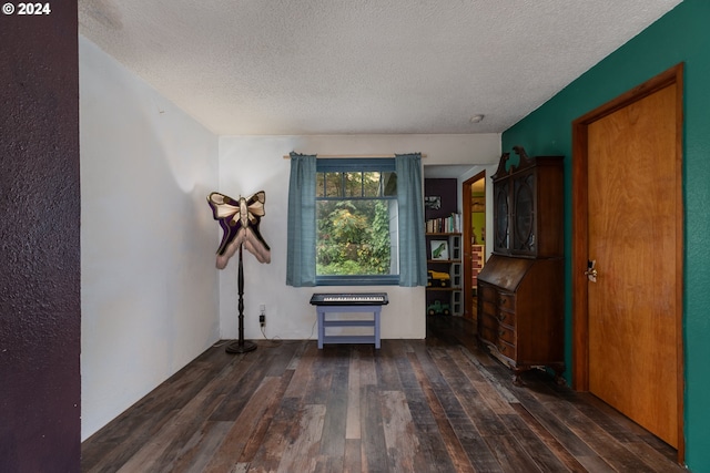 empty room featuring dark wood-type flooring and a textured ceiling