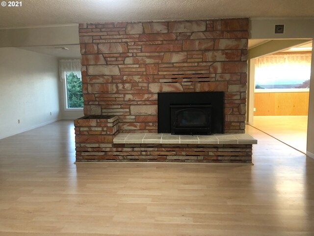 interior space featuring a stone fireplace, a textured ceiling, and light hardwood / wood-style floors