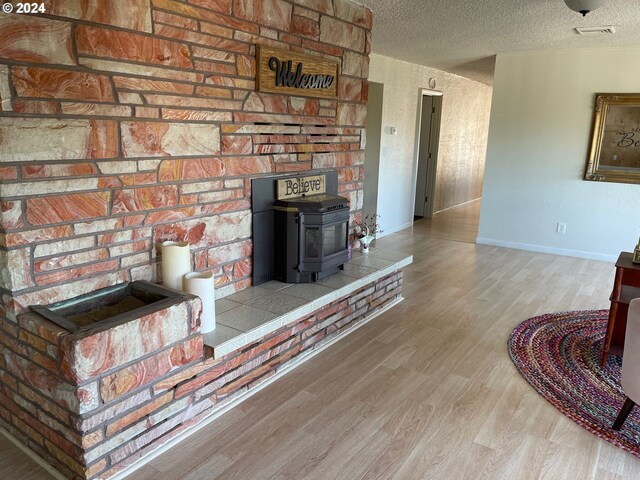 living room with a textured ceiling, light hardwood / wood-style flooring, and a wood stove