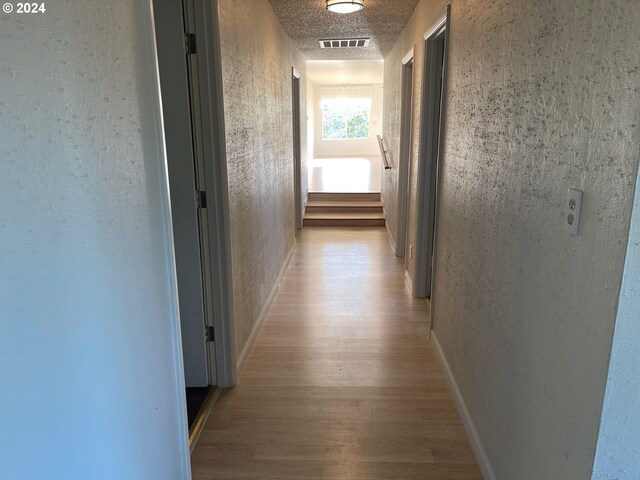 hall featuring a textured ceiling and light wood-type flooring