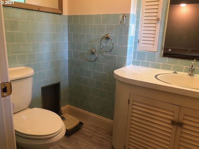 bathroom featuring tile walls, wood-type flooring, vanity, and toilet