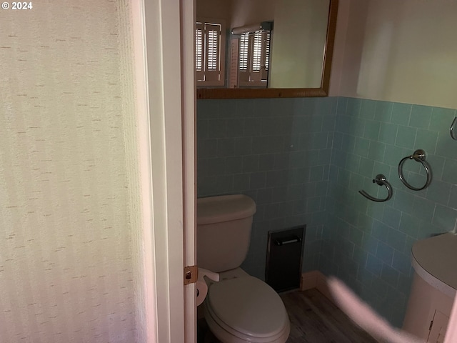 bathroom with tile walls, hardwood / wood-style flooring, and toilet