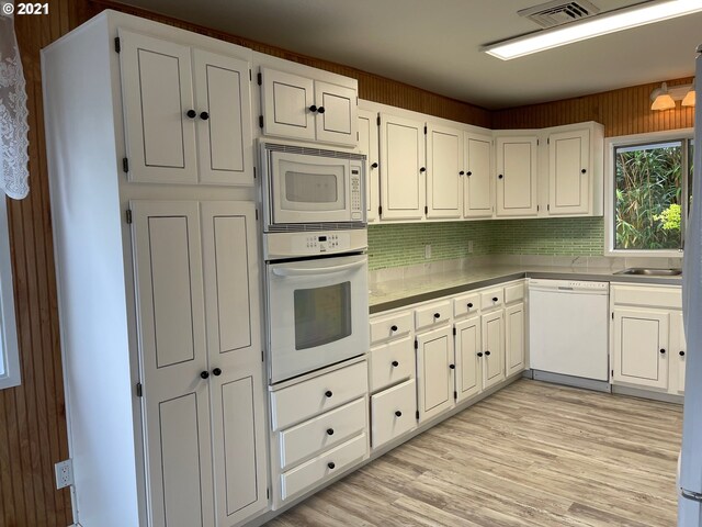 kitchen with white appliances, light hardwood / wood-style flooring, tasteful backsplash, and white cabinets