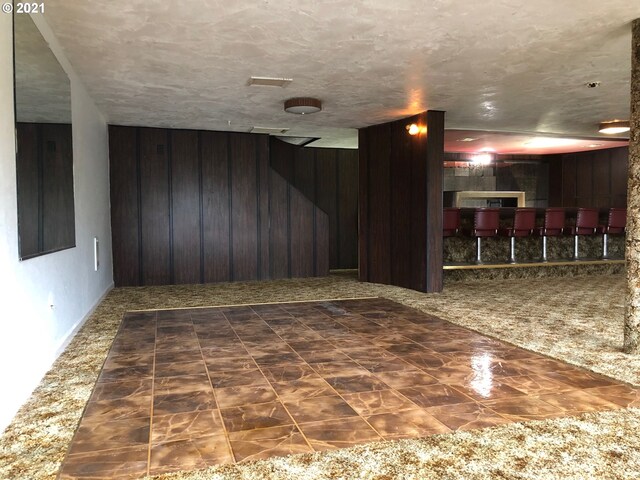 carpeted spare room with wooden walls