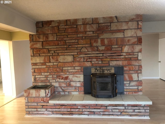 details with a textured ceiling, hardwood / wood-style floors, and a wood stove