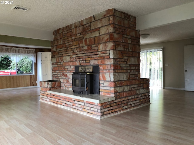 unfurnished living room featuring a wood stove, light hardwood / wood-style floors, and plenty of natural light