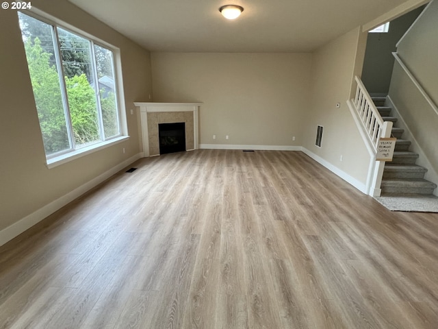 unfurnished living room featuring light hardwood / wood-style floors and a tiled fireplace