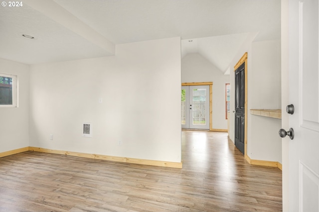 unfurnished room featuring french doors, vaulted ceiling, and light wood-type flooring