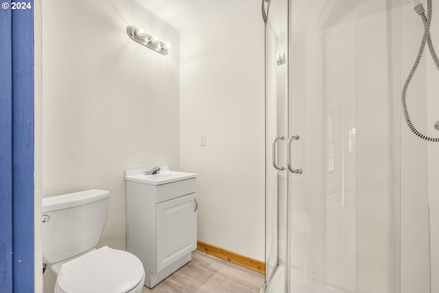 bathroom featuring vanity, wood-type flooring, toilet, and an enclosed shower