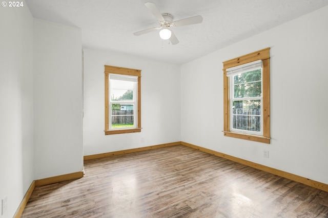 unfurnished room featuring wood-type flooring, a healthy amount of sunlight, and ceiling fan