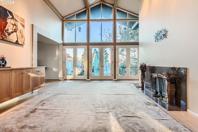 living room with a healthy amount of sunlight, light hardwood / wood-style flooring, high vaulted ceiling, and french doors