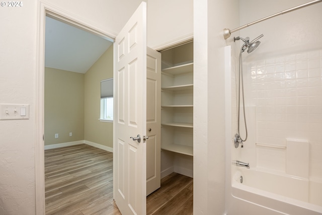 bathroom featuring shower / washtub combination, vaulted ceiling, and hardwood / wood-style flooring