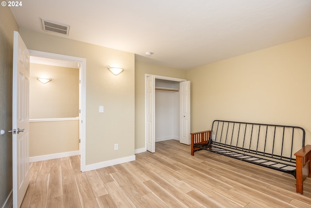 unfurnished bedroom featuring baseboards, a closet, light wood-style flooring, and visible vents