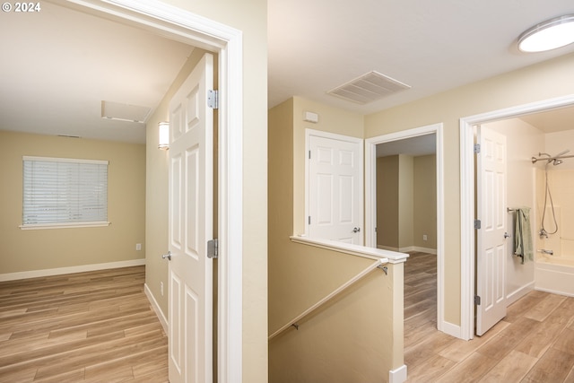 hallway featuring attic access, baseboards, visible vents, an upstairs landing, and light wood-type flooring
