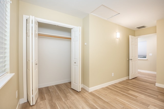 unfurnished bedroom featuring baseboards, a closet, light wood-type flooring, and visible vents