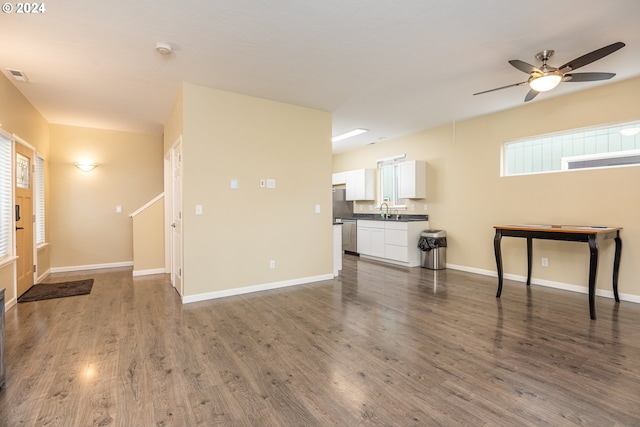 unfurnished living room featuring a healthy amount of sunlight, sink, ceiling fan, and dark wood-type flooring