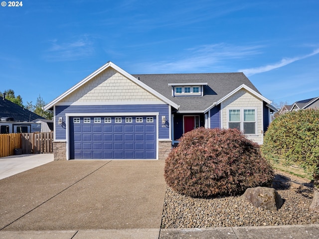 craftsman-style home featuring an attached garage, fence, stone siding, driveway, and roof with shingles