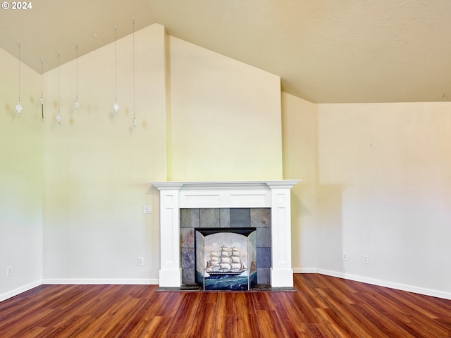 unfurnished living room with vaulted ceiling, wood finished floors, a tile fireplace, and baseboards