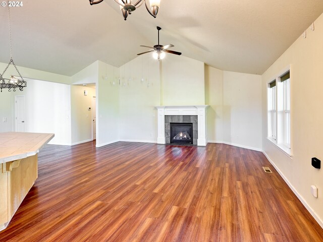 unfurnished living room with ceiling fan, dark wood-type flooring, vaulted ceiling, and a tile fireplace