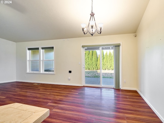 unfurnished room with an inviting chandelier, baseboards, and wood finished floors