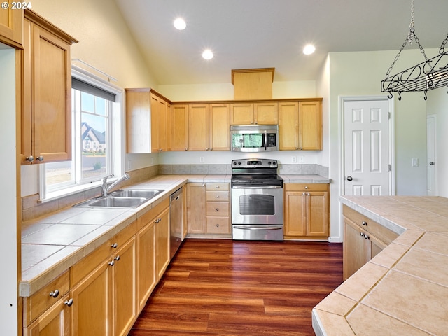 kitchen featuring tile countertops, stainless steel appliances, light brown cabinetry, and a sink