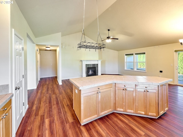 kitchen featuring light brown cabinets, a fireplace, tile counters, and open floor plan