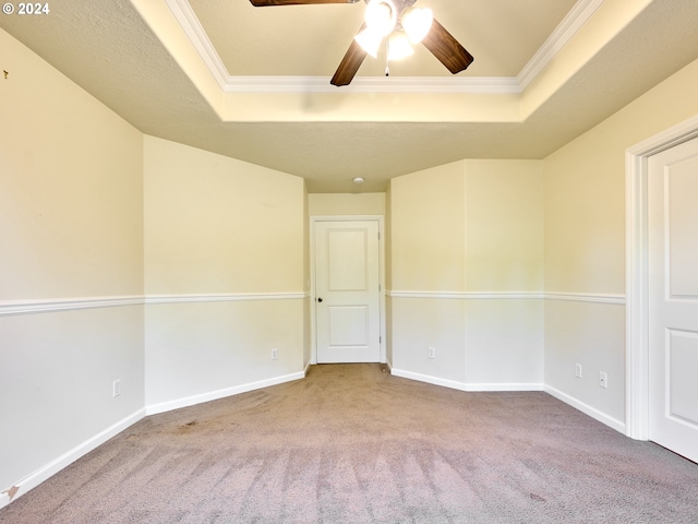 carpeted empty room featuring ceiling fan, ornamental molding, a raised ceiling, and baseboards