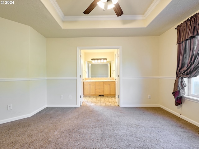 spare room with crown molding, a tray ceiling, baseboards, and light colored carpet