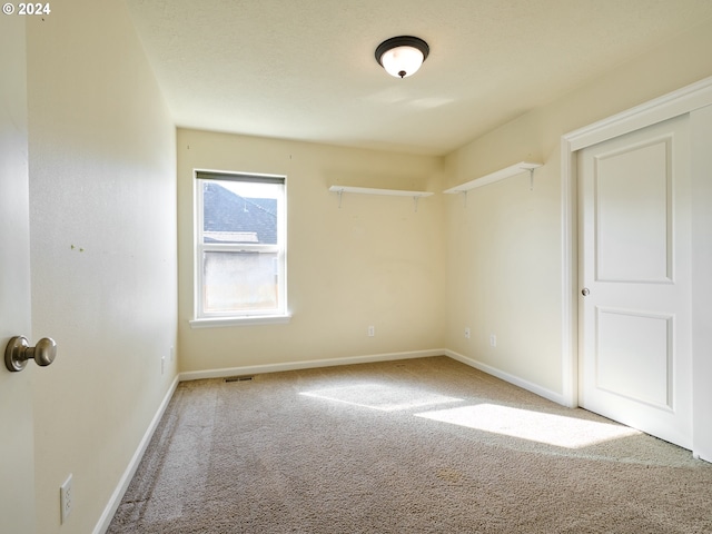 carpeted spare room with visible vents and baseboards