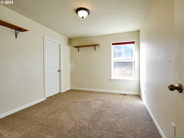 carpeted empty room featuring baseboards and a textured ceiling