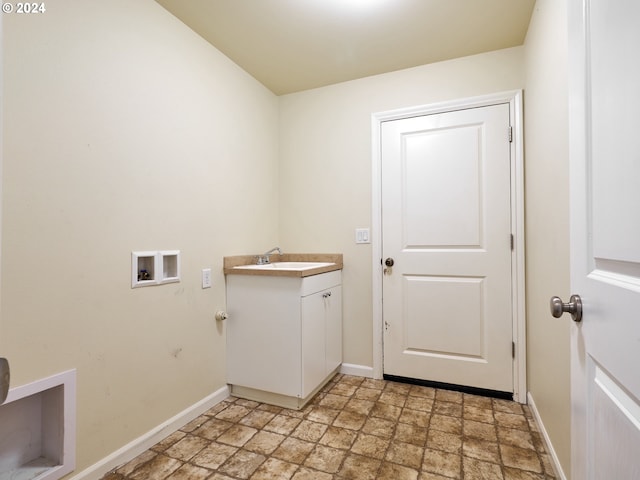 washroom featuring washer hookup, a sink, baseboards, cabinet space, and stone finish flooring