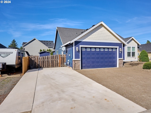 view of front of house featuring stone siding, fence, an attached garage, and concrete driveway